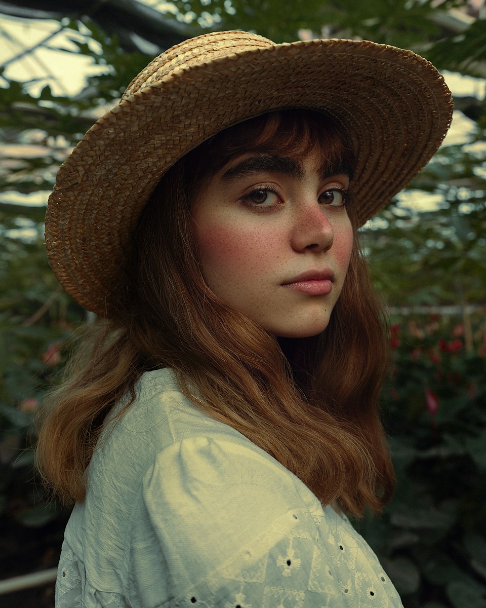 a woman wearing a straw hat in a greenhouse